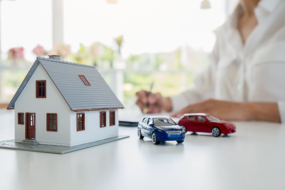 Person signing papers with model house and car in front